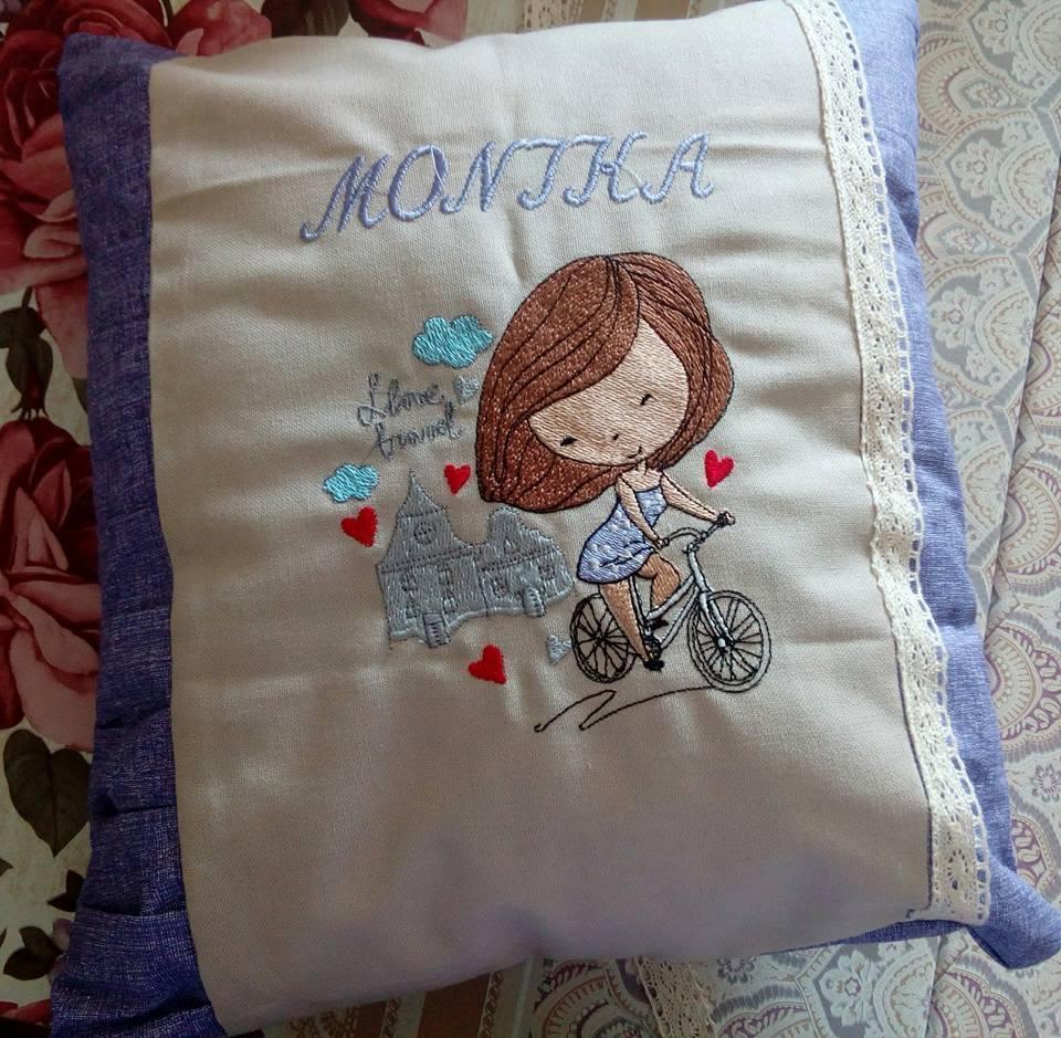 Embroidered pillow with girl on bicycle design