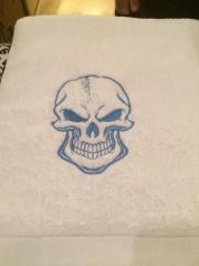 Embroidered towel with smiling skull design