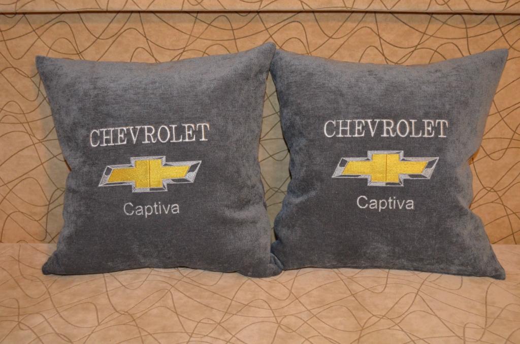 A pillow with an embroidered Chevrolet Captiva logo on it
