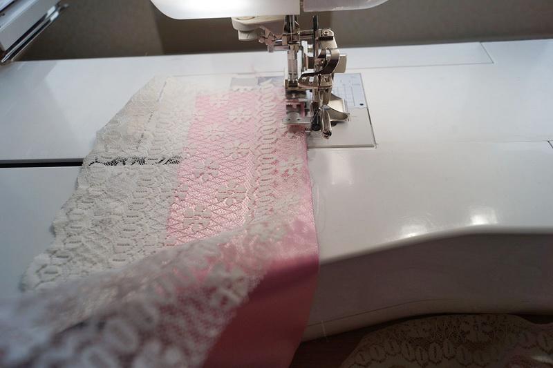 Pushing lace and lining under the foot Stitching white lace to pink fabric