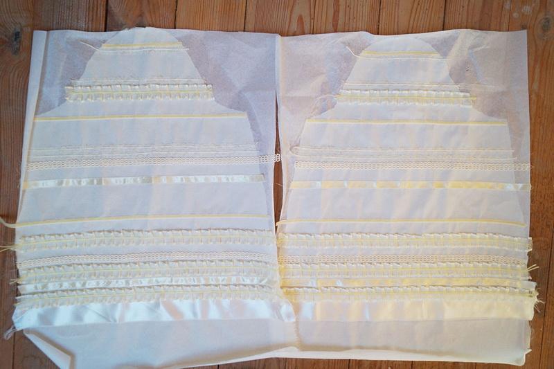 Laying ribbons out on the unstitched sleeves White ruffles on white unstitched sleeves
