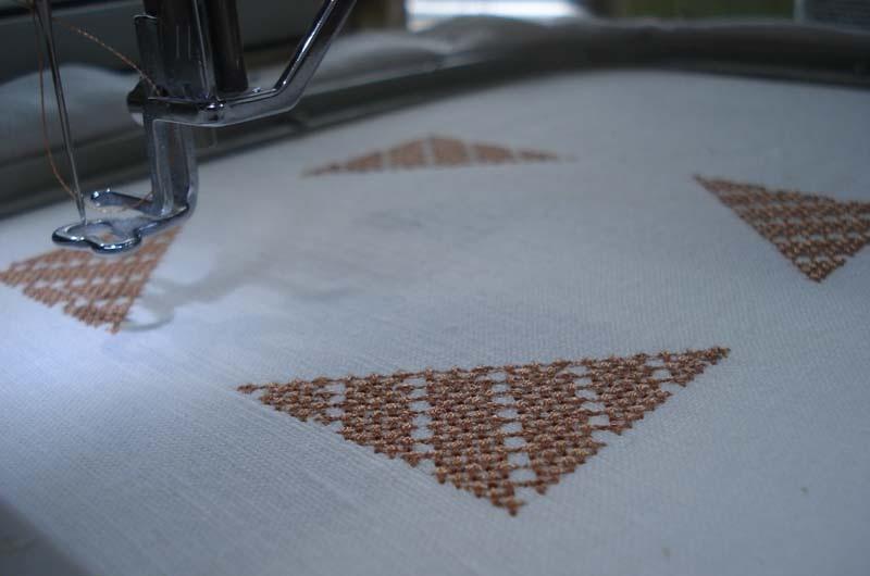 Embroidering the design on halves of biscornu White fabric with embroidery