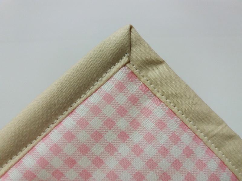 Adding binding along the edges Corner of a pot holder with binding