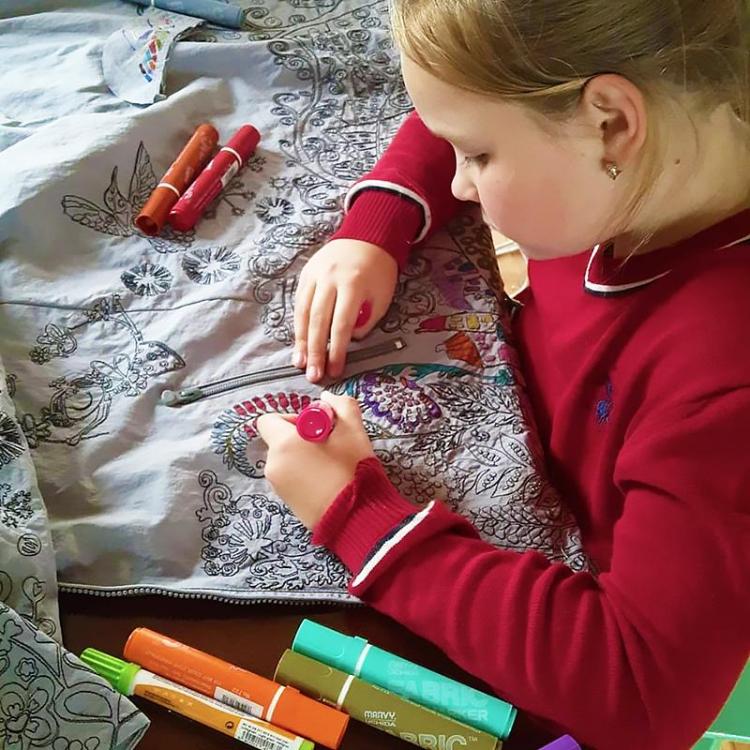 Child coloring a raincoat with embroidery