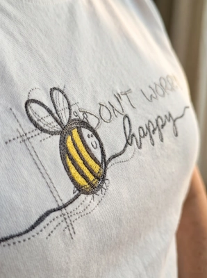 Close-up of Don't worry bee happy embroidery - bee and script detail